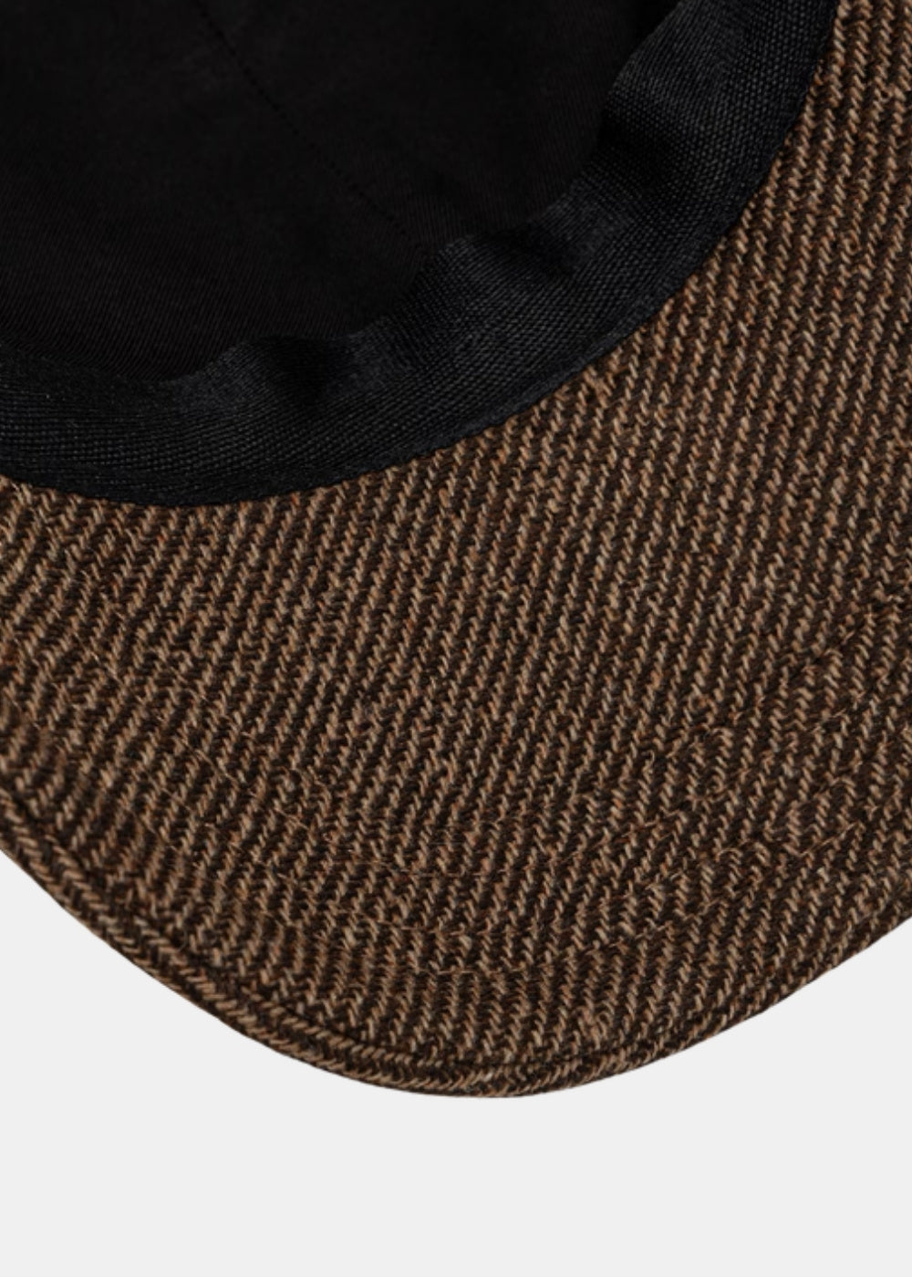 Gros plan sur la sous-visière noire et le tissu chiné marron d'une casquette baseball A.P.C. Charlie.