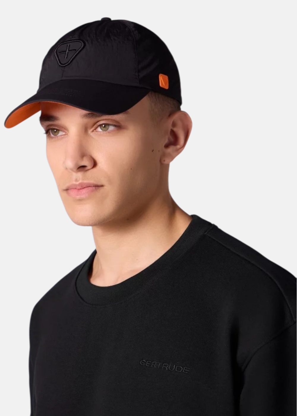 Homme portant la casquette noire Gertrude Jaron avec une doublure de visière orange contrastante.