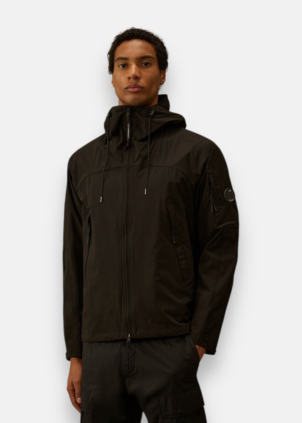 Homme portant la veste noire C.P. Company Pro-Tek zippée avec capuche ajustée.