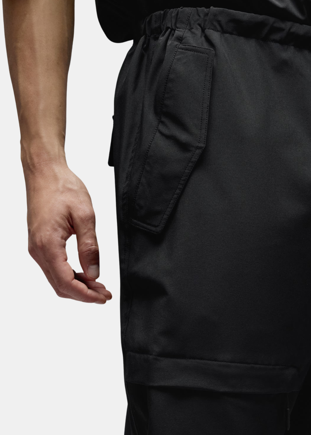 Zoom sur la poche latérale à rabat et la texture du tissu technique noir du pantalon Oakley.