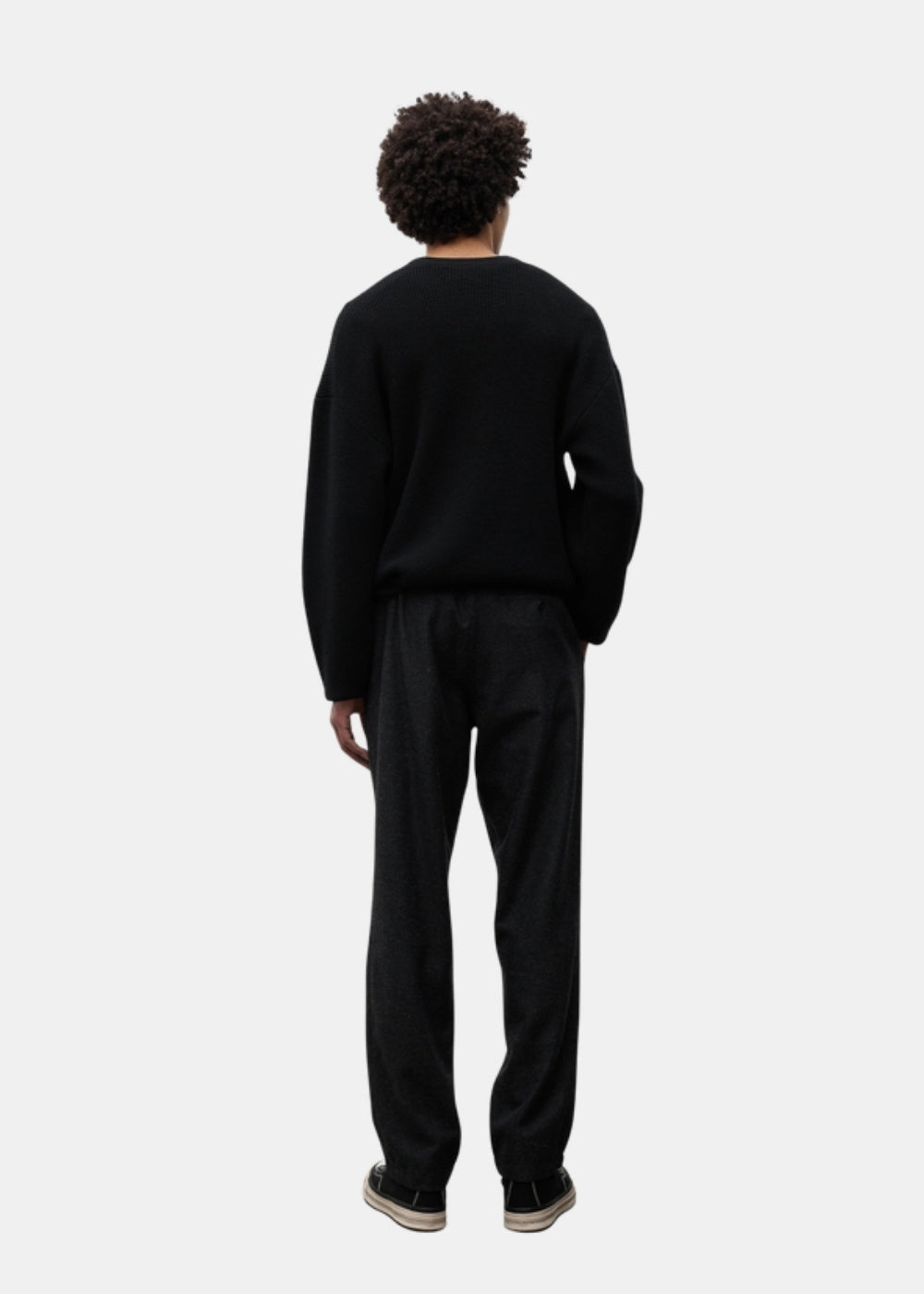 Porté de dos d'un pantalon regular gris anthracite Norse Projects Trysil associé à un pull sombre et des baskets noires.