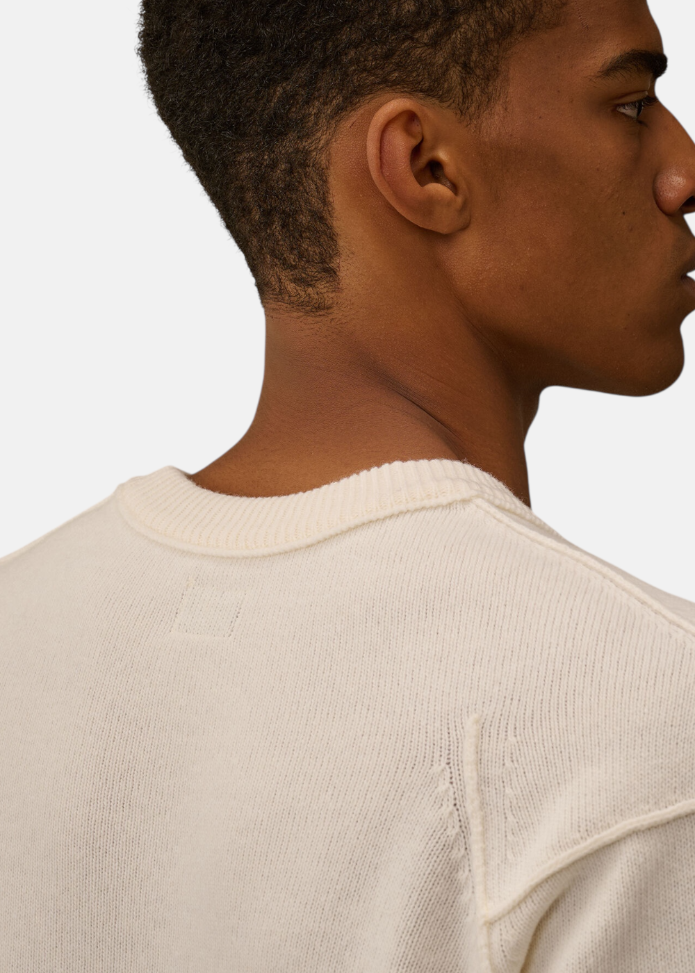Gros plan sur le col rond et les coutures contrastées du pull C.P. Company Lambswool.