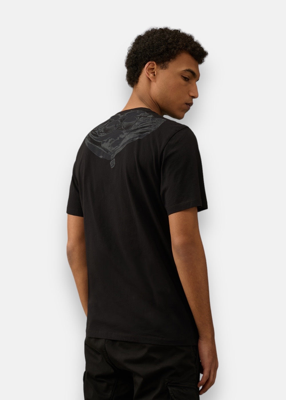 Homme portant le T-shirt C.P. Company noir, vue de profil montrant le motif Goggle Hood dans le dos.