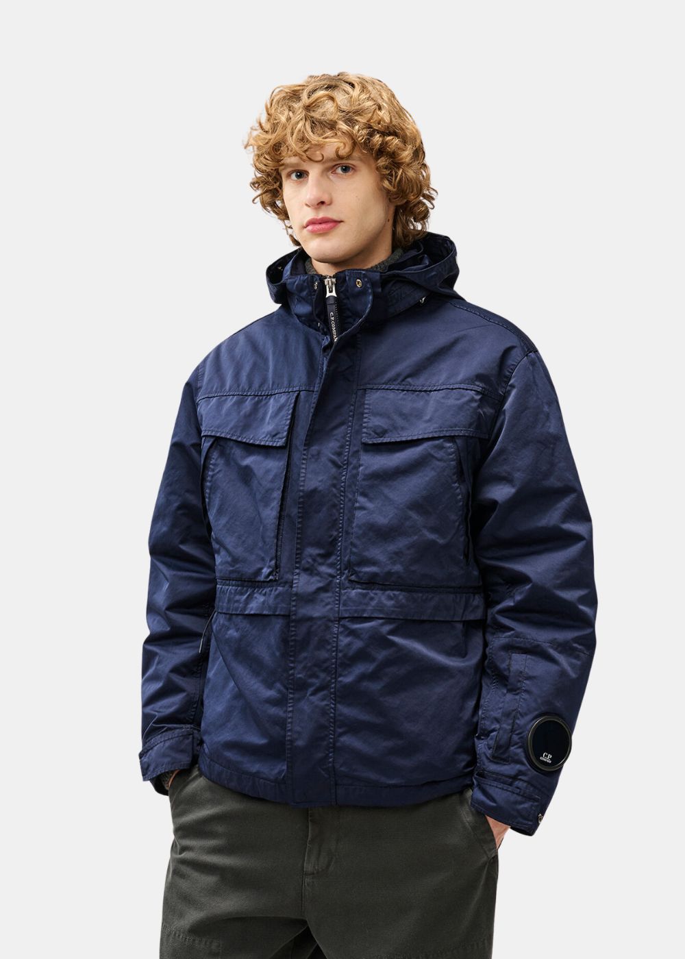 Plan moyen du mannequin portant la veste Mille C.P. Company bleue avec la lentille mate au poignet.