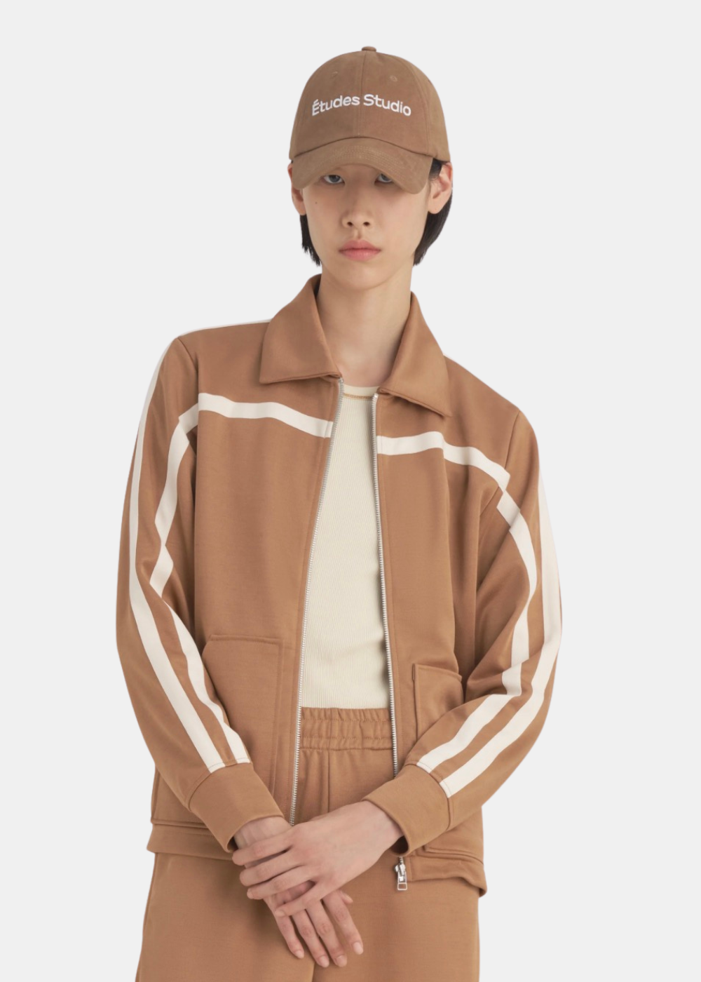 Femme portant la veste de survêtement Études Studio marron, silhouette moderne de face avec col montant.