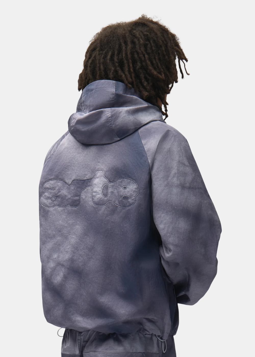 Zoom porté sur le dos de la veste Arte bleu gris mettant en valeur la capuche et le logo Arte grand format en relief.