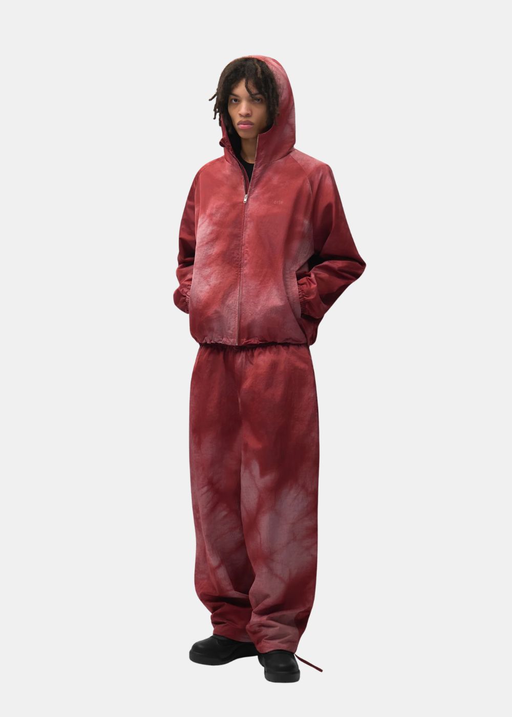 Look complet de face avec la veste à capuche Arte bordeaux zippée portée avec son pantalon assorti.